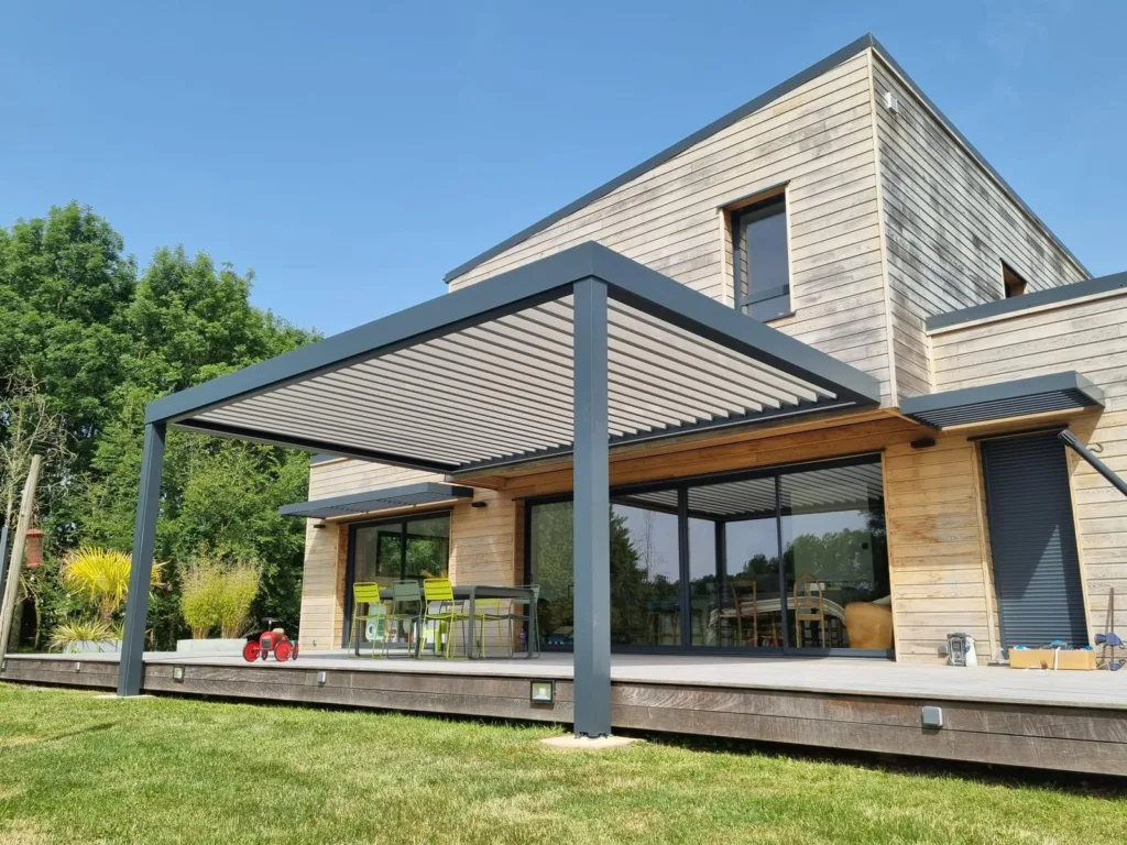 pergola bioclimatique normandie concept alu posée sur une grande maison en bardage bois en normandie